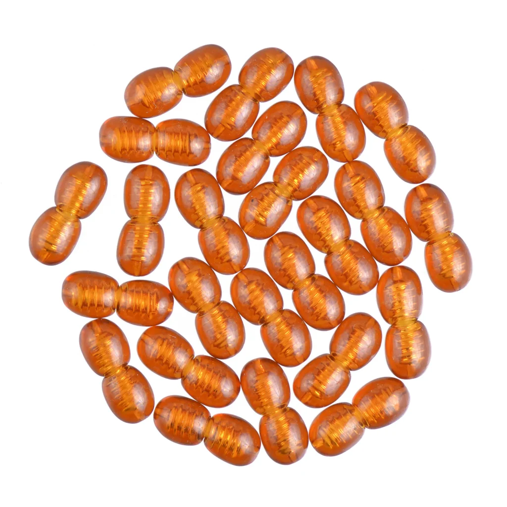 Collection of translucent amber oval beads arranged in a circular, decorative pattern with glossy finish.