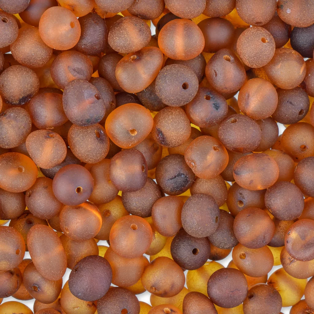 Close-up of warm, translucent amber beads in rich cognac tones for jewelry making.