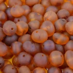 Natural Baltic amber beads in warm cognac tones with glossy, organic-centered design.