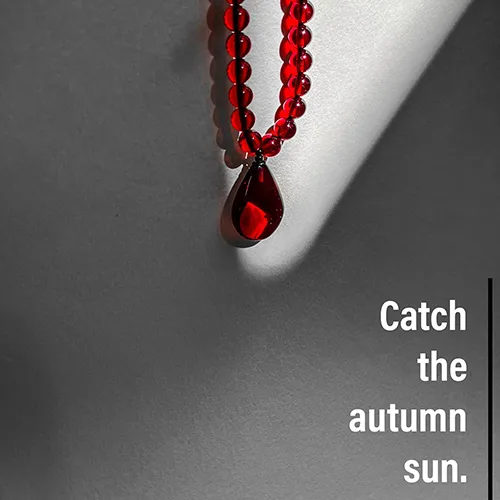 Autumn-inspired red bead necklace with teardrop amber pendant capturing seasonal warmth and elegance.