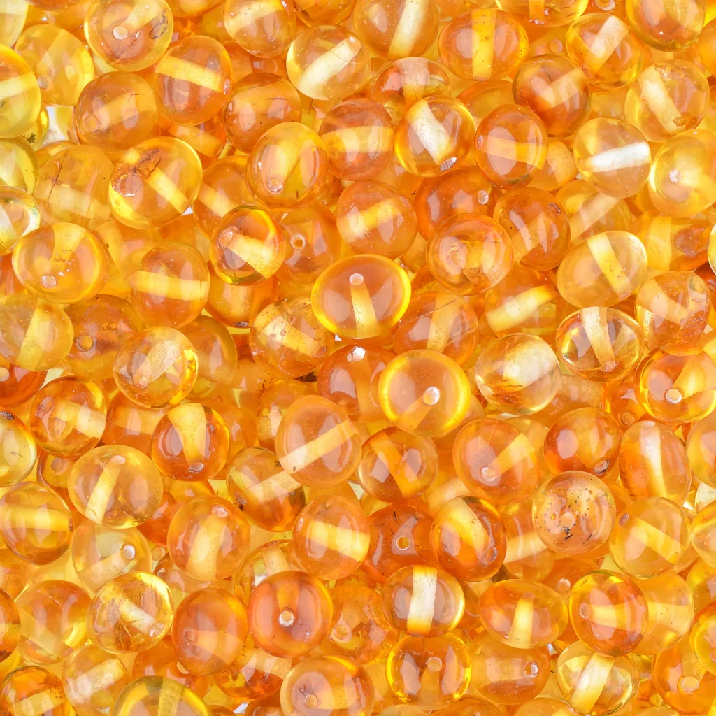 Vibrant collection of translucent amber beads in warm honey and orange tones for jewelry and crafts.