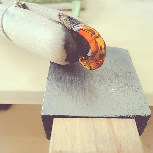 Close-up of a handcrafted amber pendant being secured in a jewelers workshop.