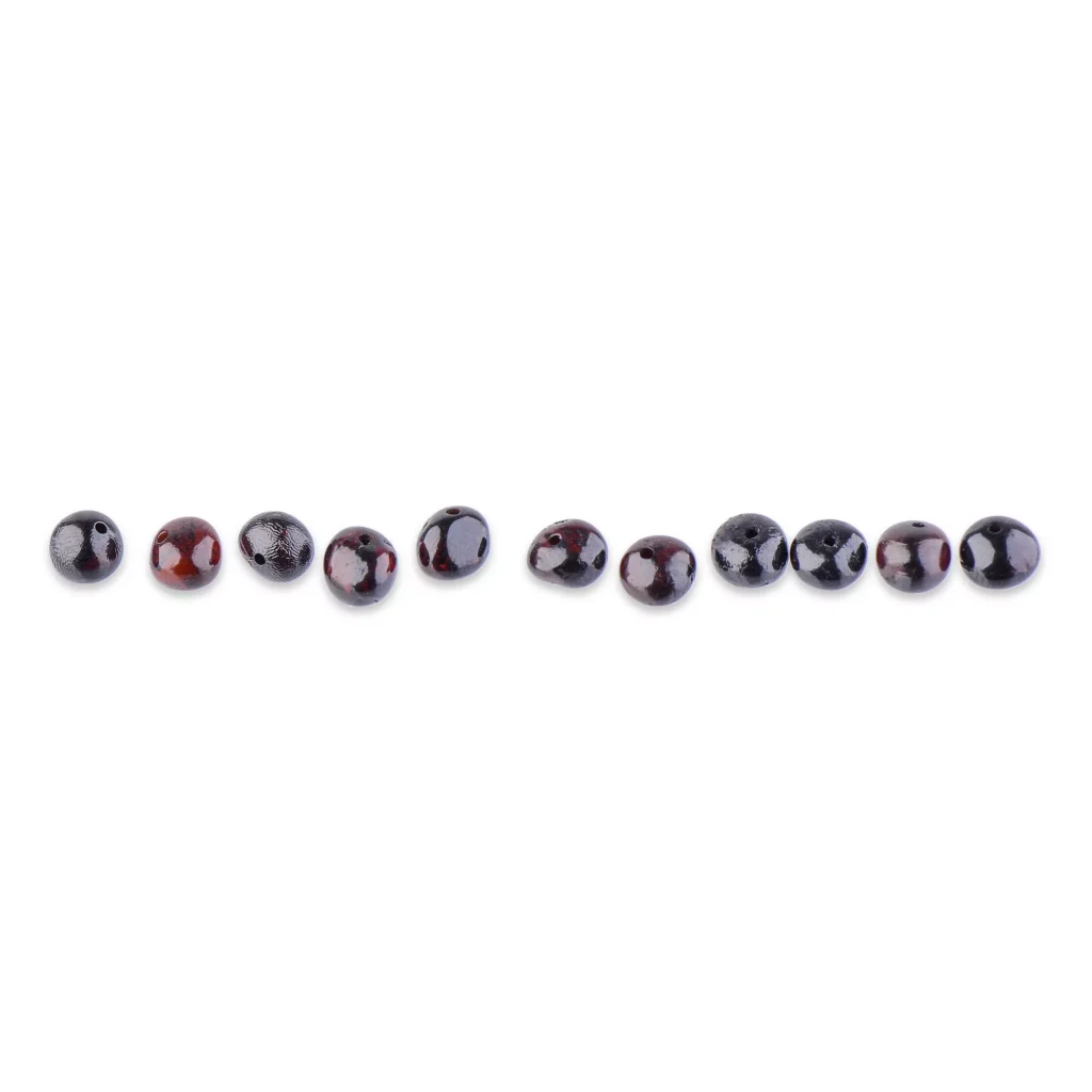Row of polished dark Baltic amber beads with elegant, reflective surfaces on minimal background.