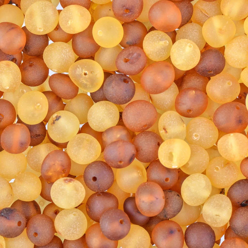 Stack of matte Baltic amber beads in warm yellow and brown tones, showcasing natural organic beauty.