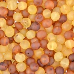 Stack of matte Baltic amber beads in warm yellow and brown tones, showcasing natural organic beauty.