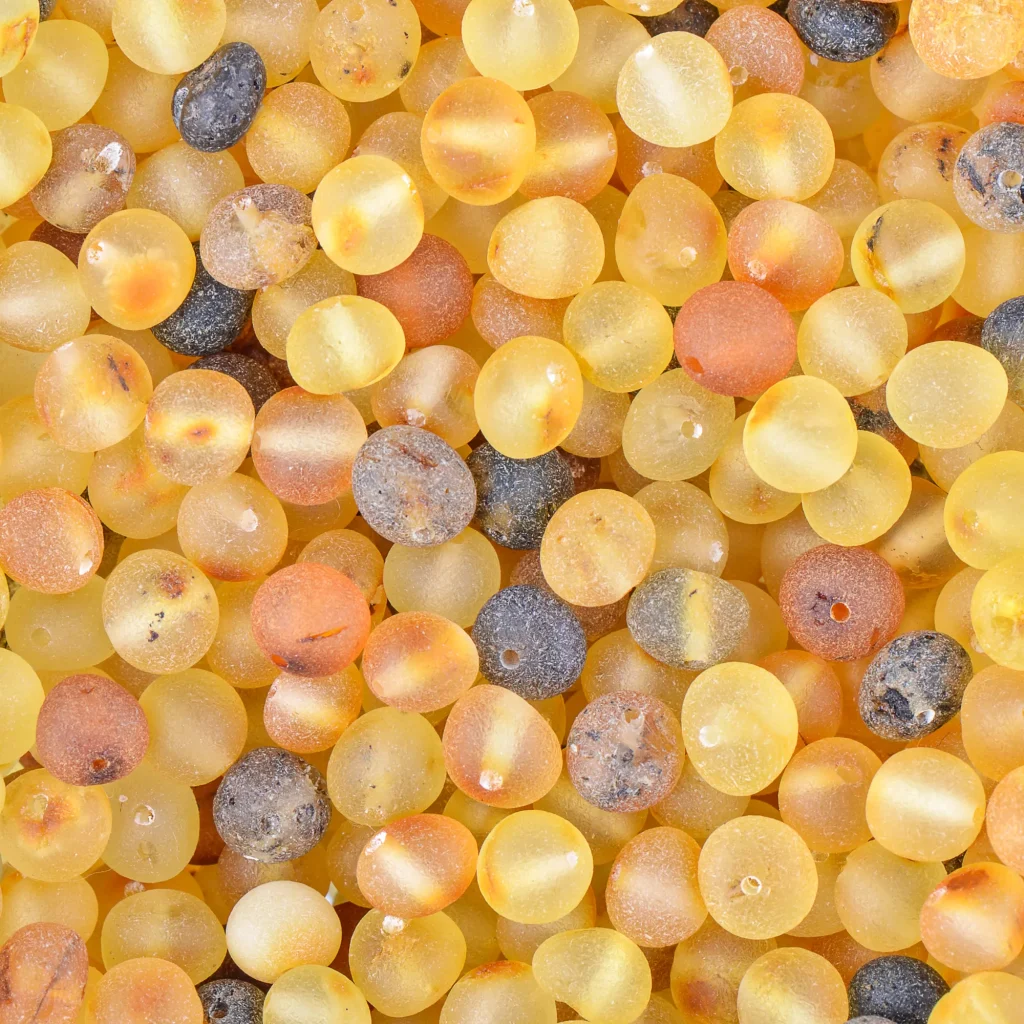 Colorful resin beads in warm yellow, orange, and black tones with glossy, translucent finishes.