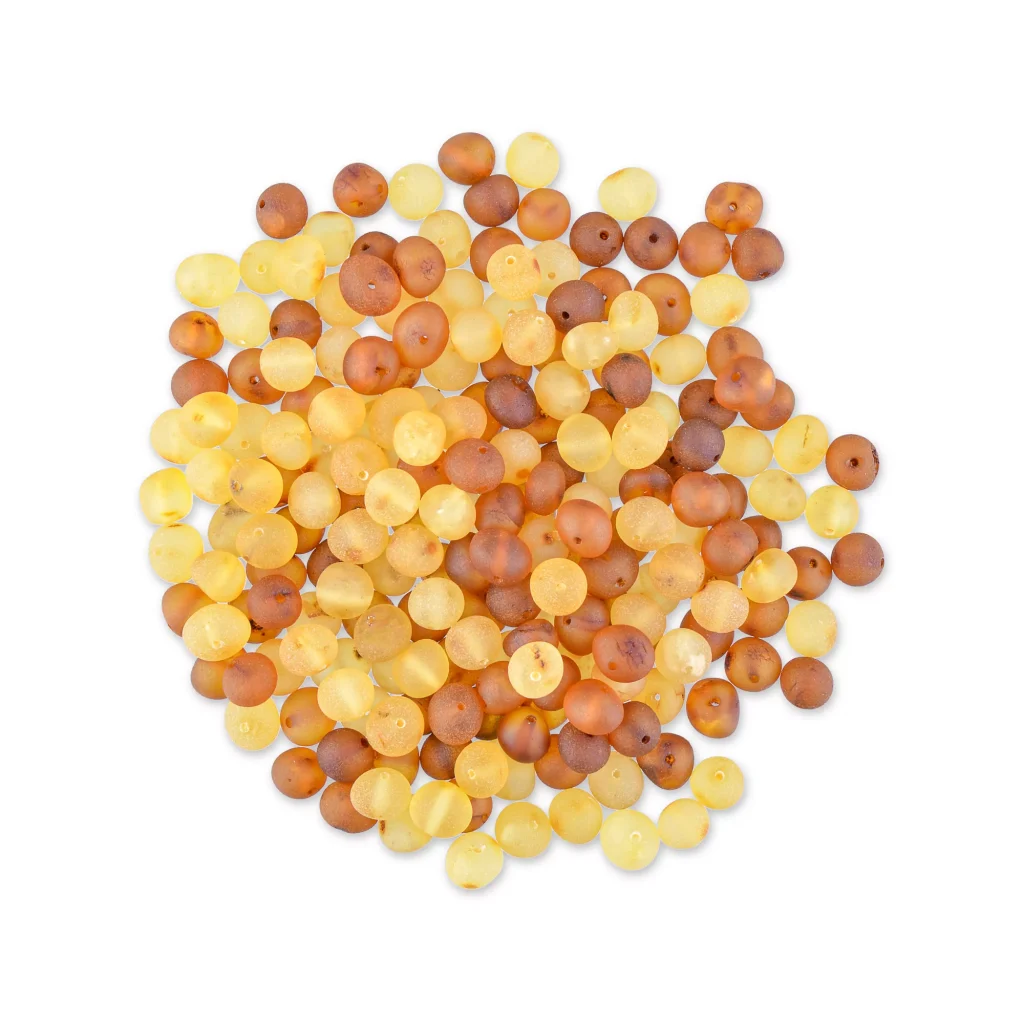 Collection of small, glossy amber beads in warm yellow, amber, and brown tones for jewelry making.