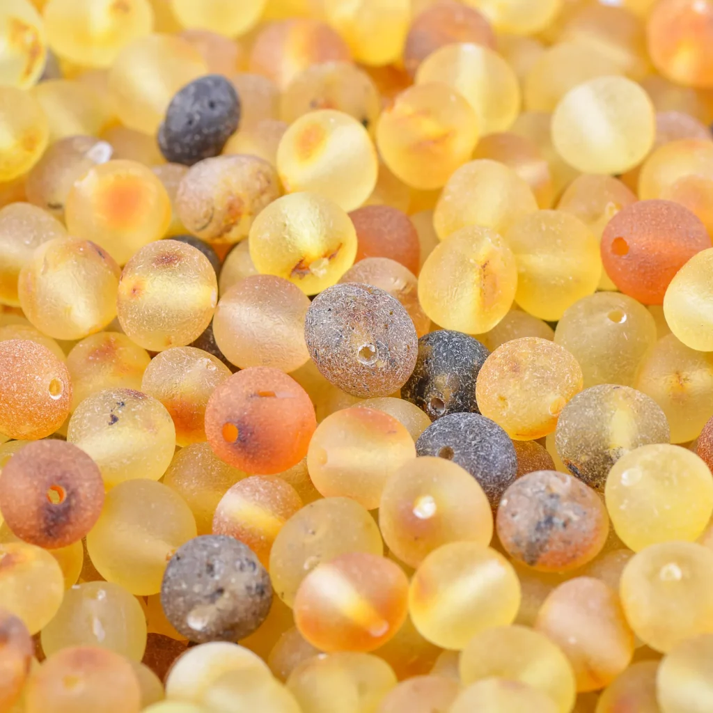 Close-up of warm amber and terracotta beads with varied textures and rich, natural tones.