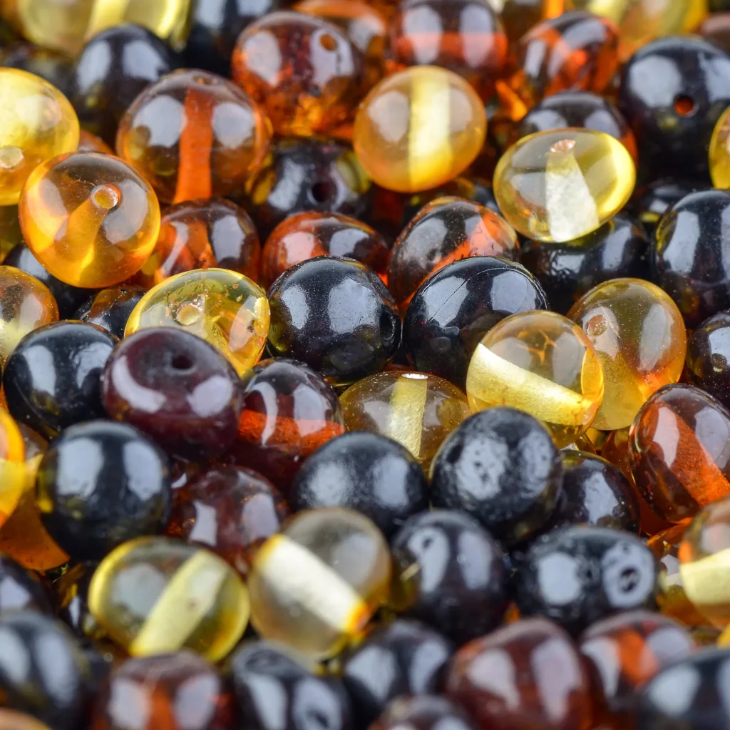 Colorful polished amber beads in black, yellow, and orange for elegant jewelry and crafts.