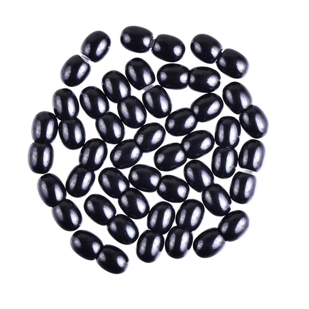 Shiny black beans arranged neatly, showcasing smooth texture and glossy finish in a minimalist design.
