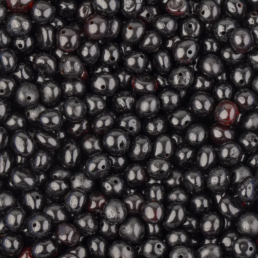 Close-up of glossy black berry-inspired Baltic amber beads on a handmade necklace.