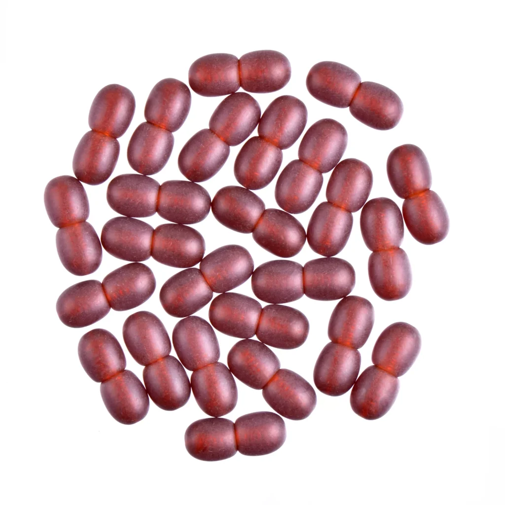 Collection of deep red, glossy capsules arranged in a circular pattern on a flat surface.