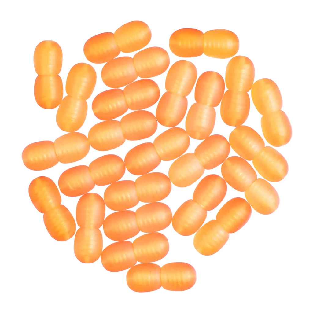 Bright orange oval capsules arranged on a white background, resembling playful candy or decorative beads.
