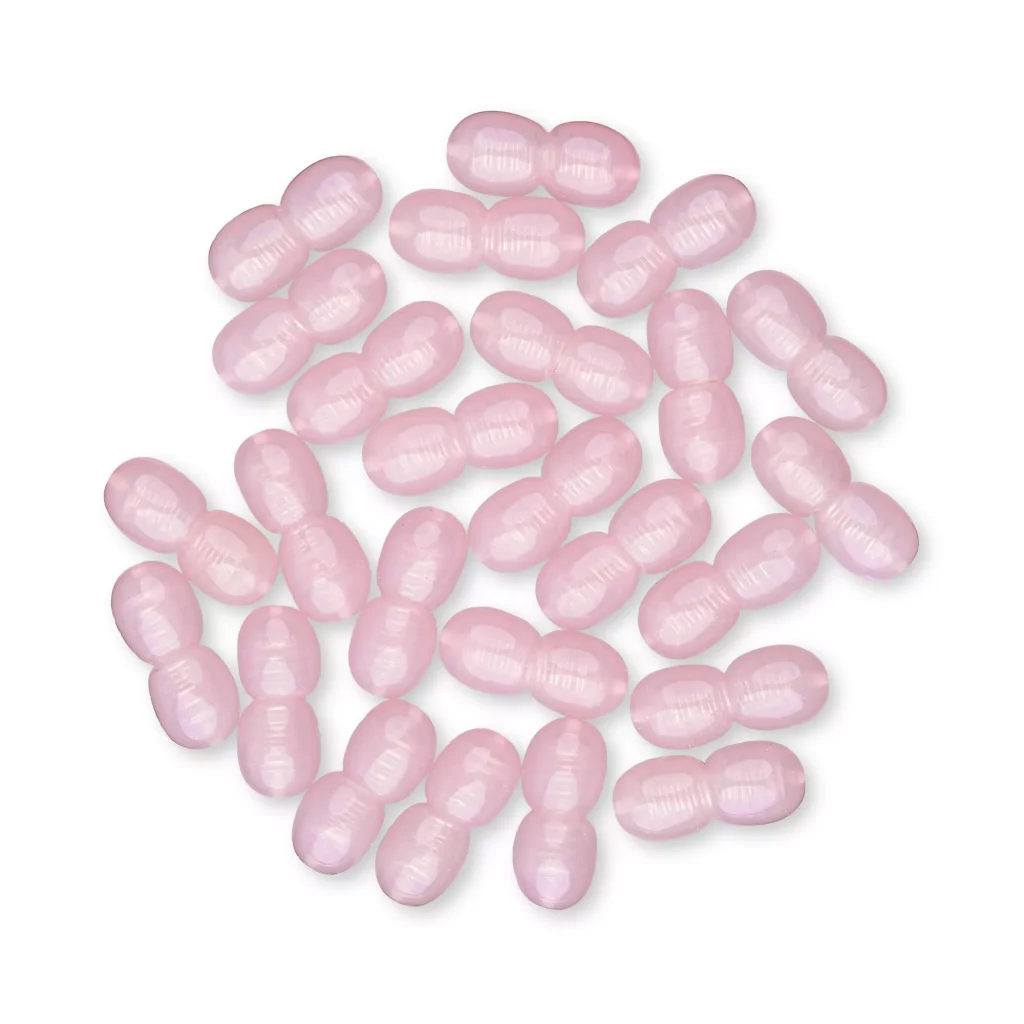 Collection of pink oval capsules, glossy, uniform, randomly scattered on plain background.