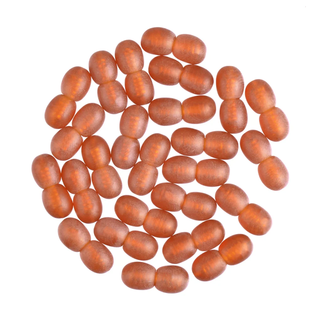 Circle of uniform amber capsules with glossy surface on a white background.