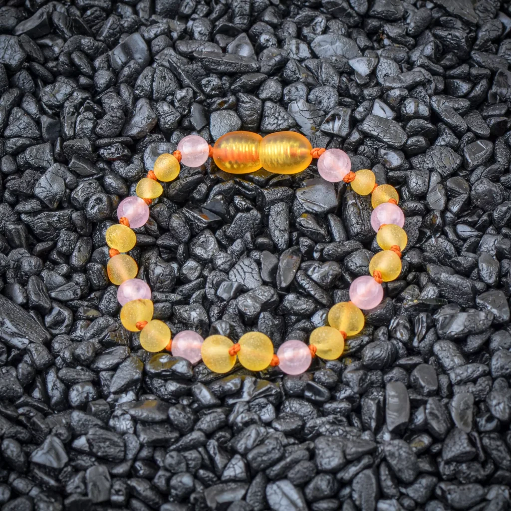 Colorful beaded bracelet with pink, yellow beads on black stones background, elegant and vibrant accessory.
