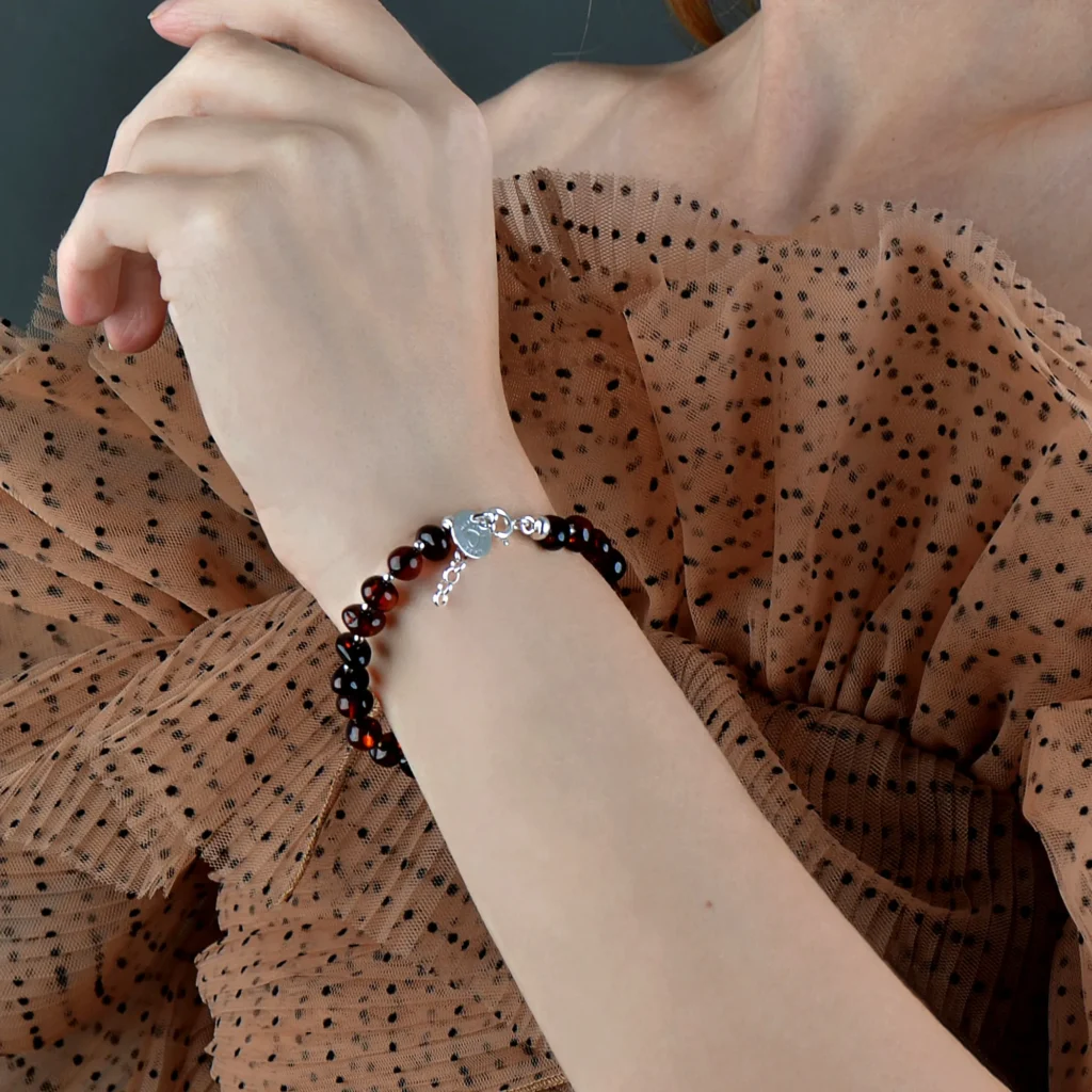 Woman wearing elegant black bead bracelet with silver accents, paired with sheer polka dot top.
