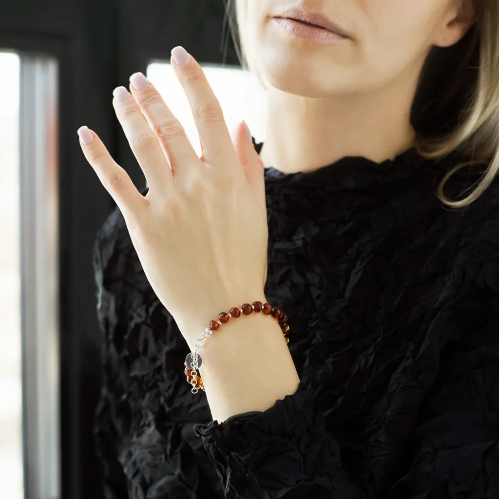 Natural Baltic amber bracelet cognac color with sterling silver accents and logo, baroque, polished, on a woman's arm