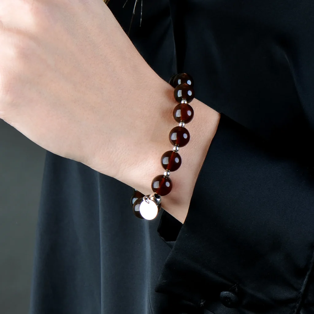 Elegant deep amber beaded bracelet with silver charm, perfect for sophisticated everyday style.