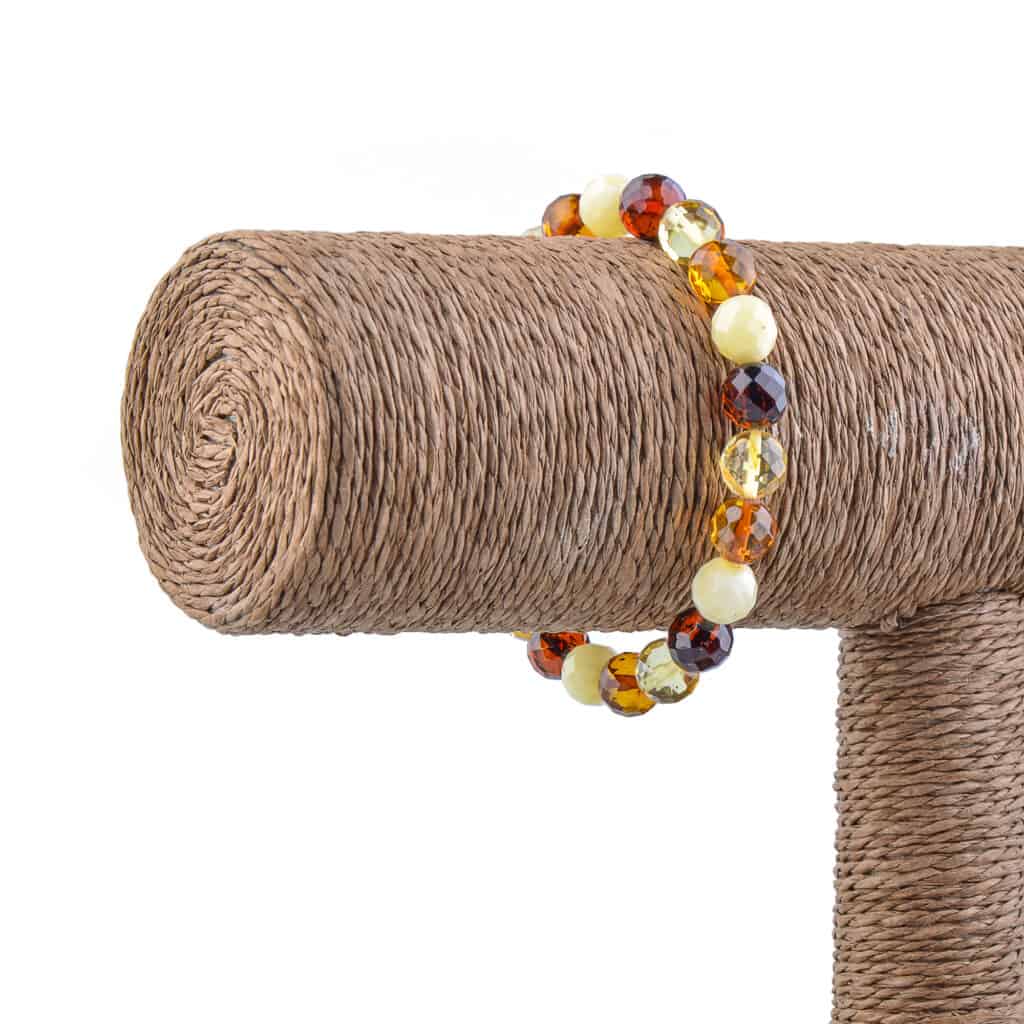 Vibrant handcrafted Baltic amber beaded bracelet displayed on rustic jute pole.