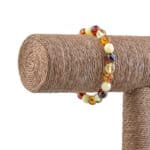 Vibrant handcrafted Baltic amber beaded bracelet displayed on rustic jute pole.