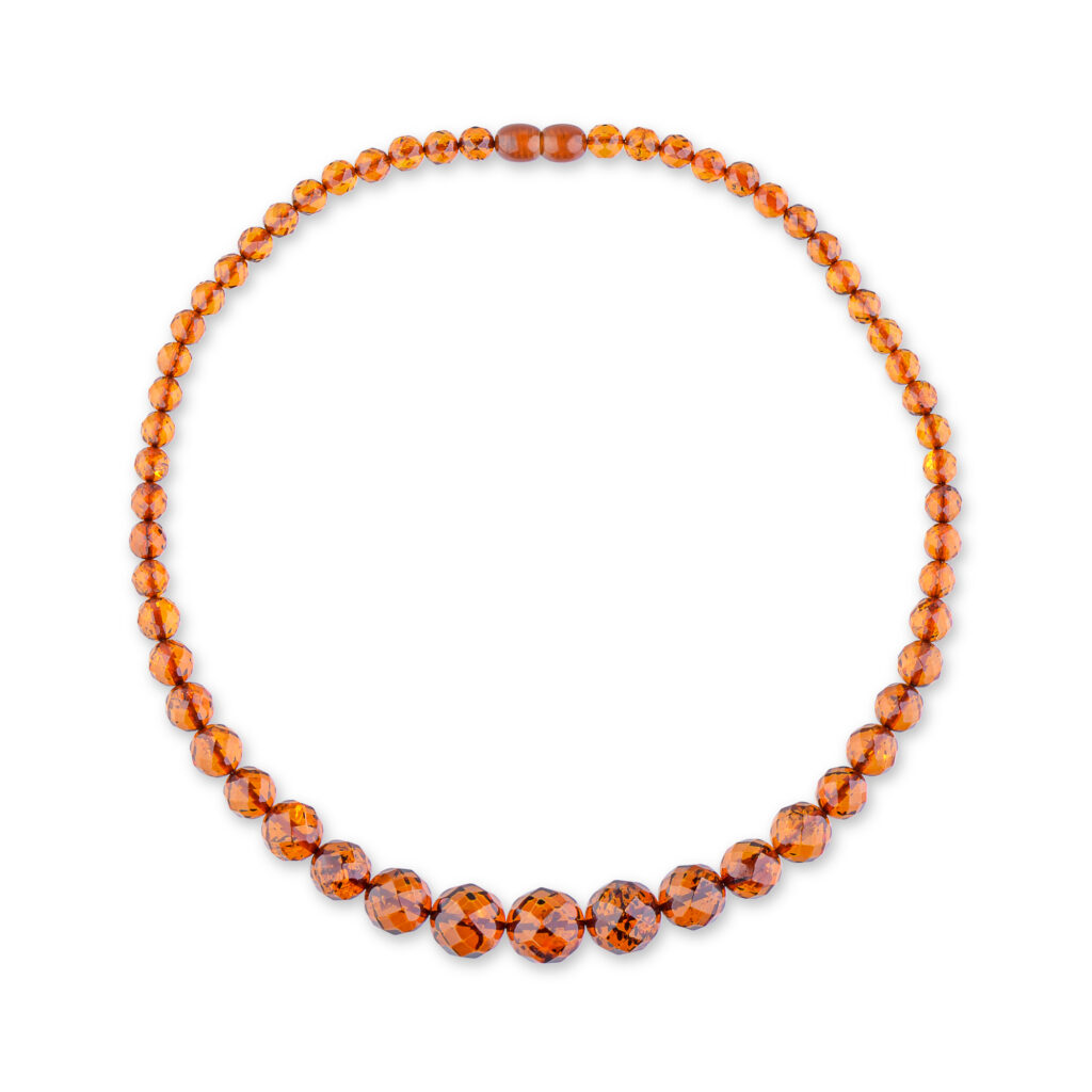 A close-up view of a genuine amber necklace, showcasing its warm, cognac-colored beads. Each bead varies slightly in shade and transparency, with natural inclusions visible inside, adding to the necklace's unique charm. The necklace is strung on a delicate chain, highlighting the organic beauty of the amber stones.