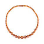 A close-up view of a genuine amber necklace, showcasing its warm, cognac-colored beads. Each bead varies slightly in shade and transparency, with natural inclusions visible inside, adding to the necklace's unique charm. The necklace is strung on a delicate chain, highlighting the organic beauty of the amber stones.