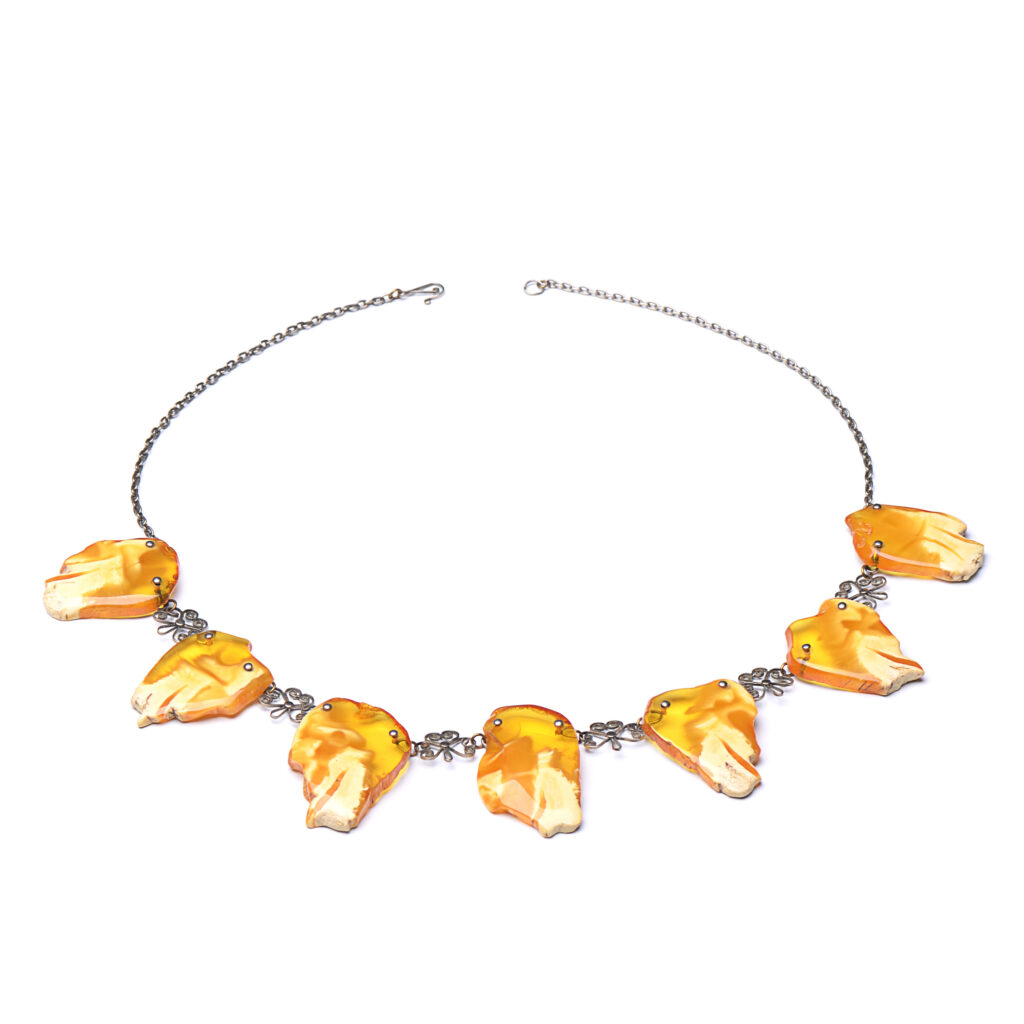 A close-up image of a genuine amber necklace, featuring smooth, polished amber beads. The beads vary slightly in size and shape, showcasing their natural organic origins. The necklace is elegantly strung together with a subtle clasp, highlighting the translucent and rich tones of the amber. The warm glow of the amber stones contrasts beautifully against the background, giving the piece a timeless and earthy appeal.