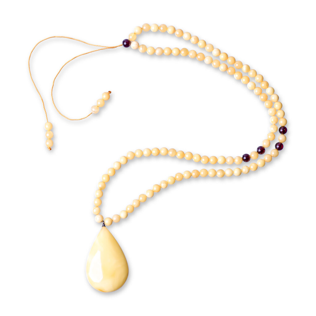 A close-up view of a genuine amber necklace, showcasing its warm, white-colored beads. Each bead varies slightly in shade and transparency, with natural inclusions visible inside, adding to the necklace's unique charm. The necklace is strung on a delicate chain, highlighting the organic beauty of the amber stones.