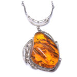 A close-up image of a genuine amber pendant showcasing its warm, golden hues. The amber is transparent with natural inclusions, capturing its organic beauty. The pendant is encased in a silver or gold frame, adding elegance to the raw, fossilized resin. The smooth surface of the amber reflects light, highlighting its natural glow and intricate details. This timeless piece of jewelry hangs delicately from a chain, blending nature and craftsmanship.