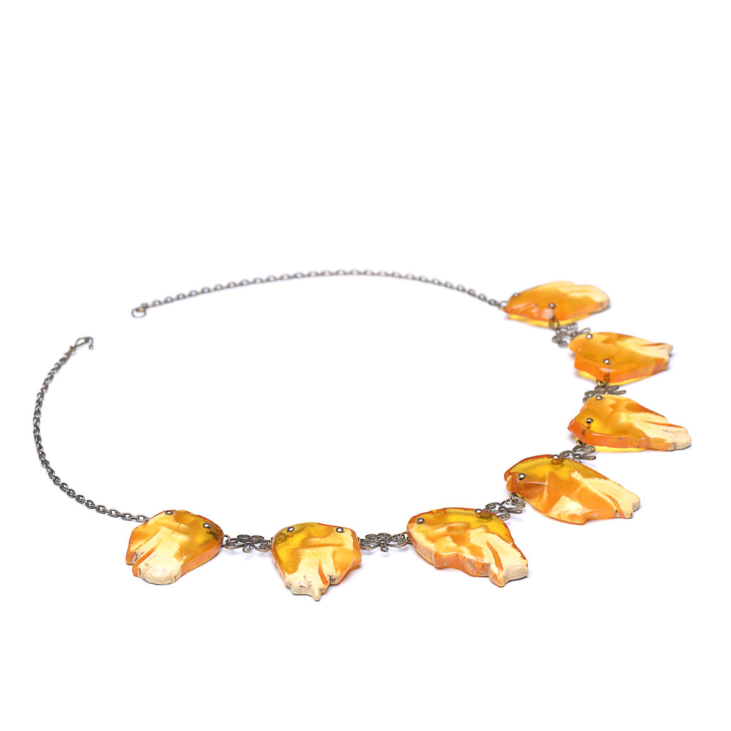 A close-up image of a genuine amber necklace, featuring smooth, polished amber beads. The beads vary slightly in size and shape, showcasing their natural organic origins. The necklace is elegantly strung together with a subtle clasp, highlighting the translucent and rich tones of the amber. The warm glow of the amber stones contrasts beautifully against the background, giving the piece a timeless and earthy appeal.