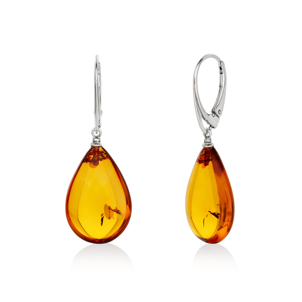 Natural amber dangling earrings, drop-shaped, cognac color with sterling silver, an earring in a woman's ear