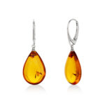 A pair of genuine amber earrings with translucent, warm golden-orange stones, showcasing natural inclusions. The amber is set in delicate silver or gold, highlighting its organic beauty. The earrings have a polished surface that reflects light, emphasizing the rich color variations and natural patterns within the amber. The earrings are lightweight, elegant, and exude a timeless, earthy charm, perfect for both casual and formal wear.