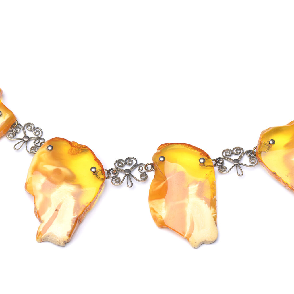 A close-up image of a genuine amber necklace, featuring smooth, polished amber beads. The beads vary slightly in size and shape, showcasing their natural organic origins. The necklace is elegantly strung together with a subtle clasp, highlighting the translucent and rich tones of the amber. The warm glow of the amber stones contrasts beautifully against the background, giving the piece a timeless and earthy appeal.