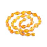 Elegant amber bead necklace with golden facets and glossy, faceted oval beads.