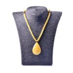 Elegant yellow beaded necklace with teardrop amber pendant on textured black display.