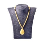Elegant yellow Baltic amber necklace with teardrop pendant on textured black display.