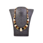 Handmade Baltic amber necklace with geometric beads on a gray jewelry display.