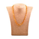 Handmade amber beaded necklace displayed on a neutral linen bust.