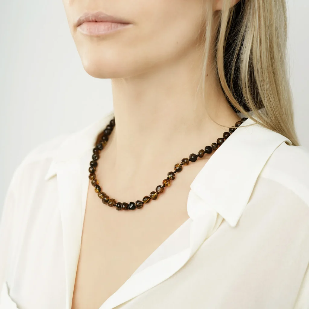 Elegant Baltic amber beaded necklace worn by stylish woman with white blouse and soft background.