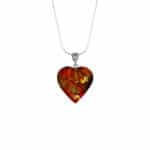 Vibrant Baltic amber heart pendant with floral accents on silver chain, stylish and natural elegance.