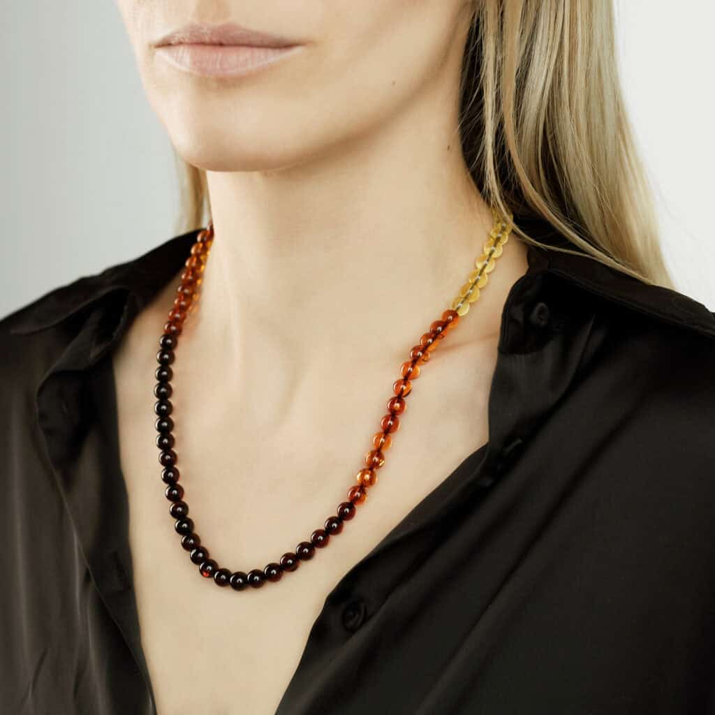 Elegant Baltic amber necklace with gradient beads worn by a woman in a black shirt.