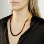 Elegant Baltic amber necklace with gradient beads worn by a woman in a black shirt.
