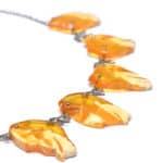 Stylish Baltic amber fish necklace with vibrant orange pendants and delicate metal chain.
