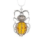 Baltic amber beetle pendant with silver details, natural warm tones, and intricate artisanal craftsmanship.