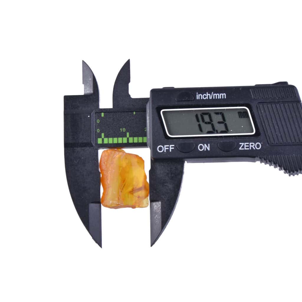 Digital caliper measuring vibrant orange mineral specimen, showing 19.3 mm in a professional setting.