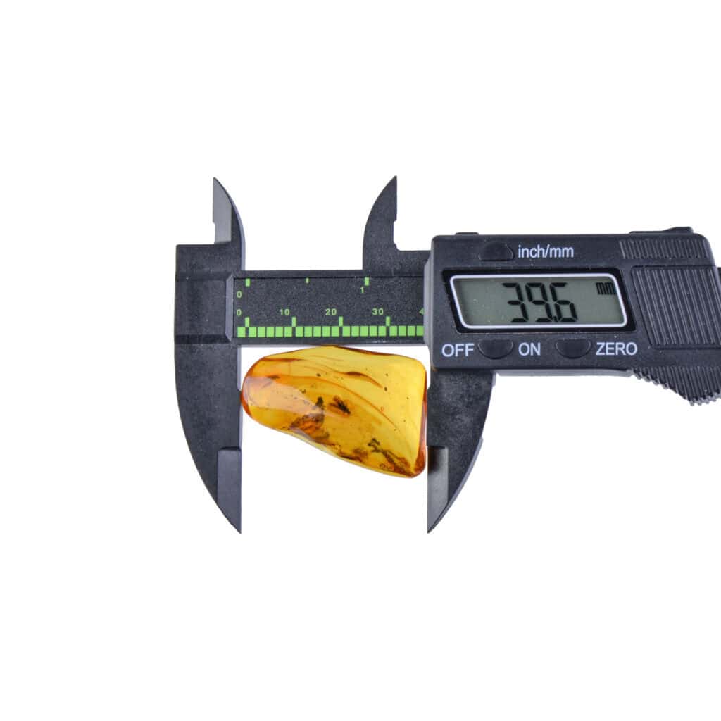 Close-up of amber being measured with digital caliper showing 39.6mm width.