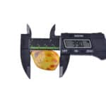 Digital caliper measuring an irregular amber piece with insect inclusion, 39.0 mm in size.