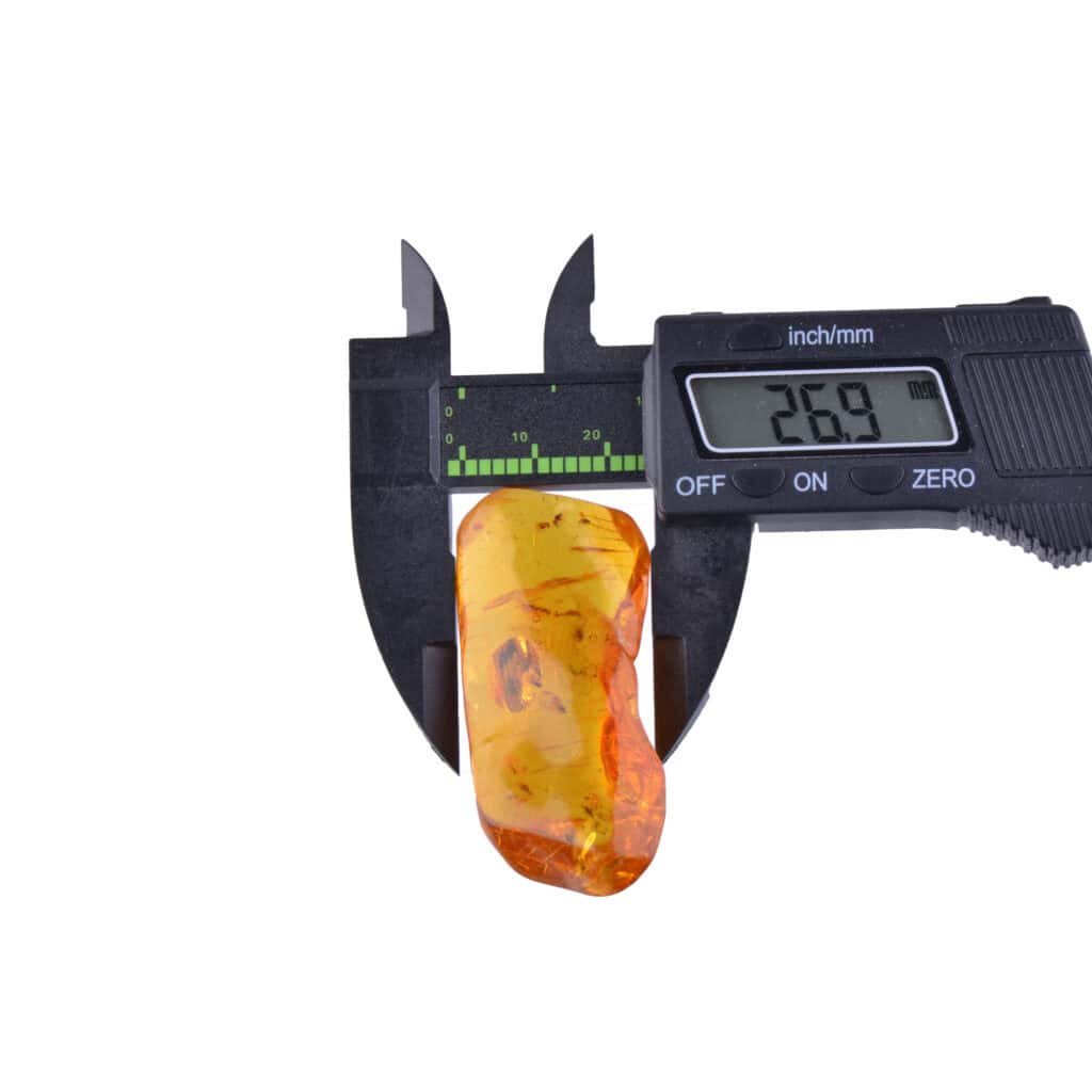 Amber specimen measured with caliper, showcasing natural inclusions and rich orange-yellow color.