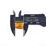 Measuring polished Baltic amber with digital caliper, showcasing natural warmth and beautiful inclusions.